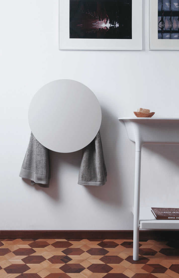 MG12 Geometrici Round towel warmer in white with towels hanging below the round heated panel in a modern bathroom - 20 inch round towel warmer