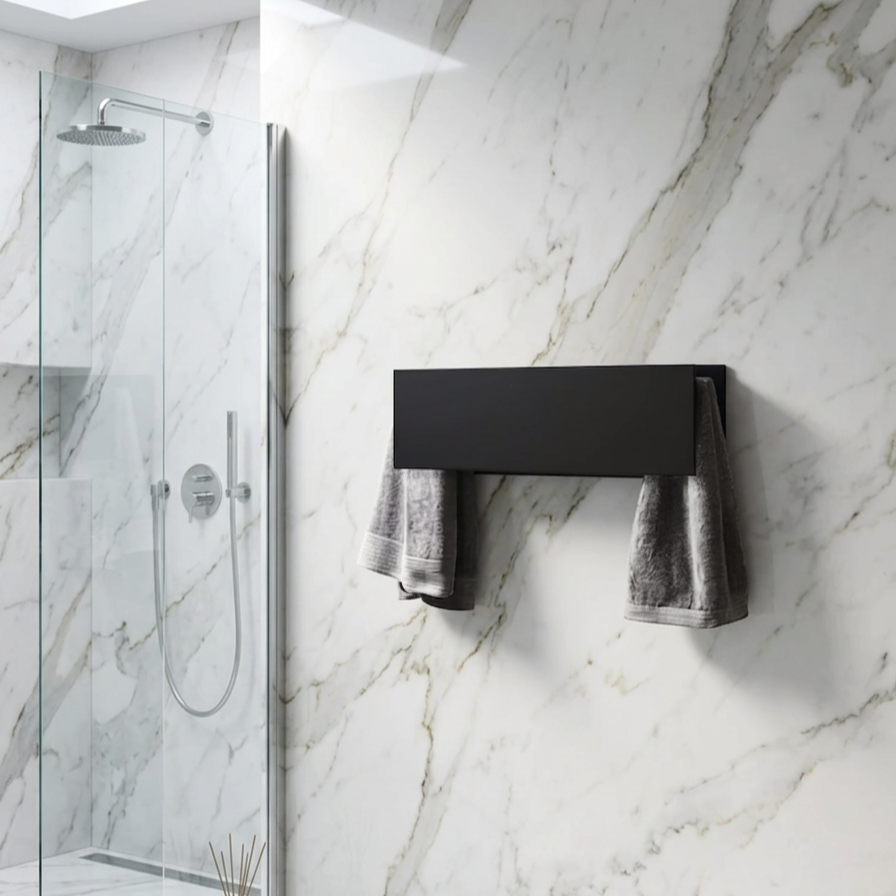 MG12 MiniSlim electric towel warmer in matte black installed on a marble bathroom wall beside a glass shower