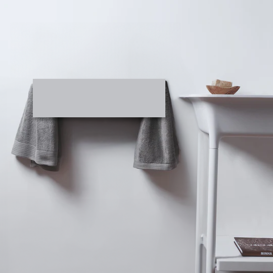 MG12 MiniSlim electric towel warmer in matte white, wall-mounted with grey towels in a minimalist bathroom